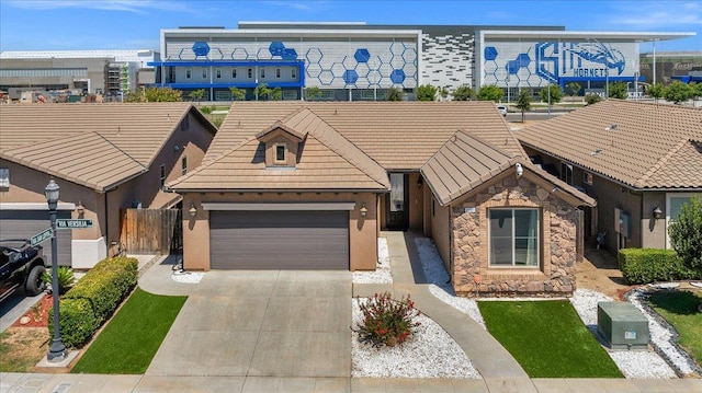 2481 S Via Versilia Dr, Fresno, CA 93727 - view of front of home with an attached garage, driveway, a tiled roof, stucco siding, and stone siding