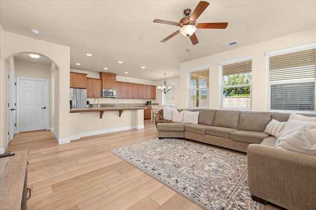 2481 S Via Versilia Dr, Fresno, CA 93727 - living room featuring arched walkways, a ceiling fan, light wood-style floors, a chandelier, and recessed lighting