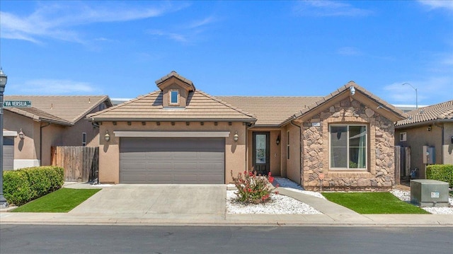2481 S Via Versilia Dr, Fresno, CA 93727 - view of front of house with an attached garage, stone siding, a tile roof, concrete driveway, and stucco siding