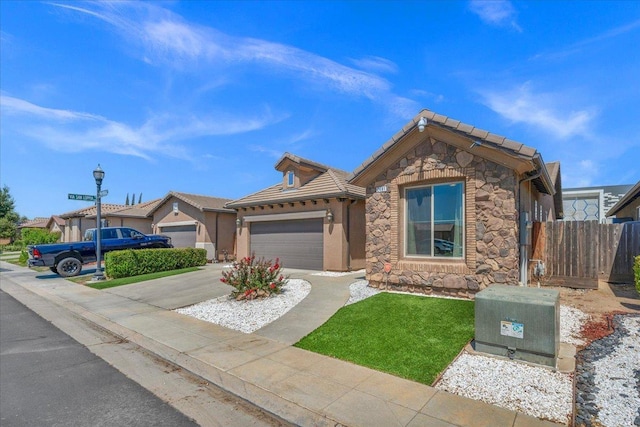 2481 S Via Versilia Dr, Fresno, CA 93727 - ranch-style house featuring stone siding, an attached garage, concrete driveway, and a tiled roof