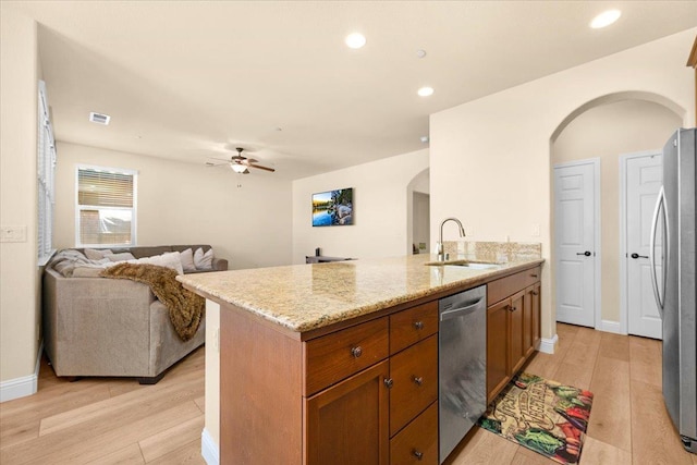 2481 S Via Versilia Dr, Fresno, CA 93727 - kitchen featuring arched walkways, appliances with stainless steel finishes, a peninsula, light wood finished floors, and brown cabinetry