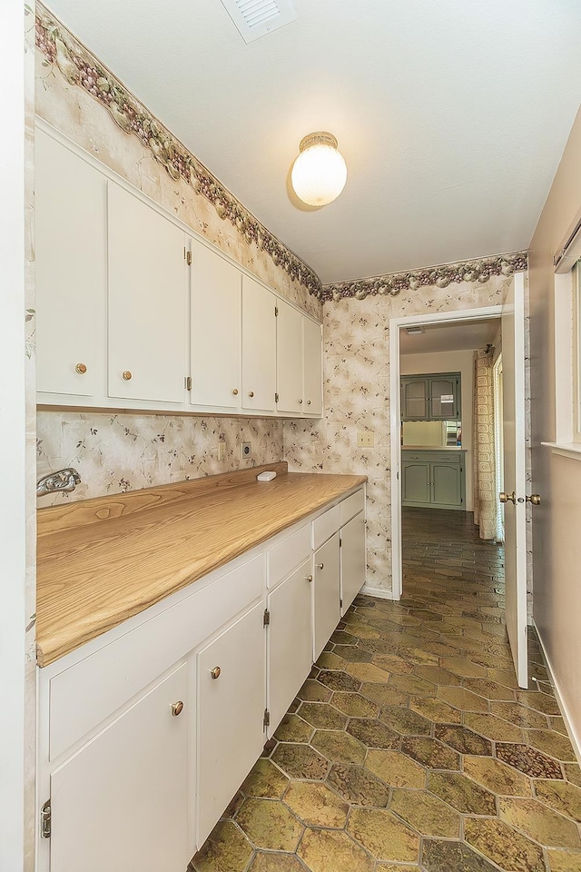 10465 E Herndon Ave, Clovis, CA 93619 - kitchen with white cabinetry, light countertops, wallpapered walls, and dark stone finish flooring