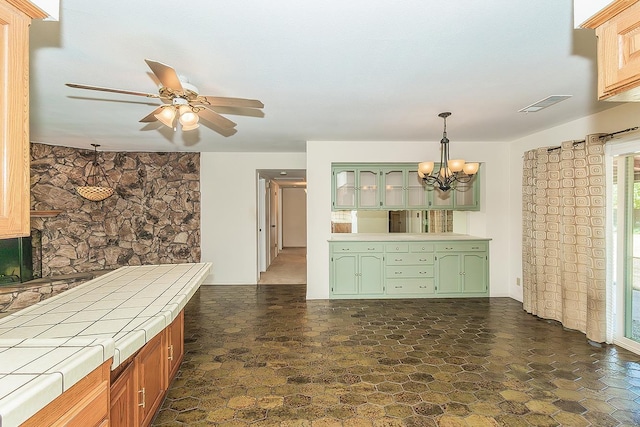10465 E Herndon Ave, Clovis, CA 93619 - kitchen with tile counters, green cabinetry, a chandelier, ceiling fan, and dark stone finish floors