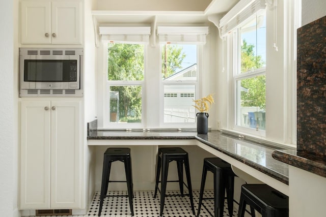 321 E Brown, Fresno, CA 93704 - kitchen with stainless steel microwave, dark stone countertops, plenty of natural light, and white cabinets