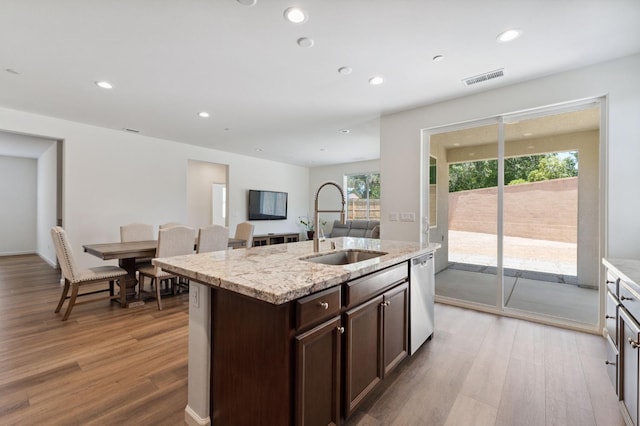 1567 Las Rosas Ave, Clovis, CA 93619 - kitchen with light wood-style flooring, dark brown cabinetry, stainless steel dishwasher, light stone countertops, and an island with sink