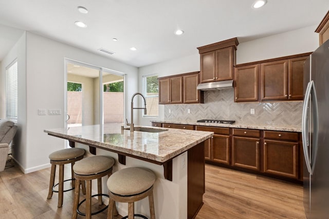 1567 Las Rosas Ave, Clovis, CA 93619 - kitchen featuring stainless steel appliances, light wood finished floors, light stone counters, backsplash, and under cabinet range hood