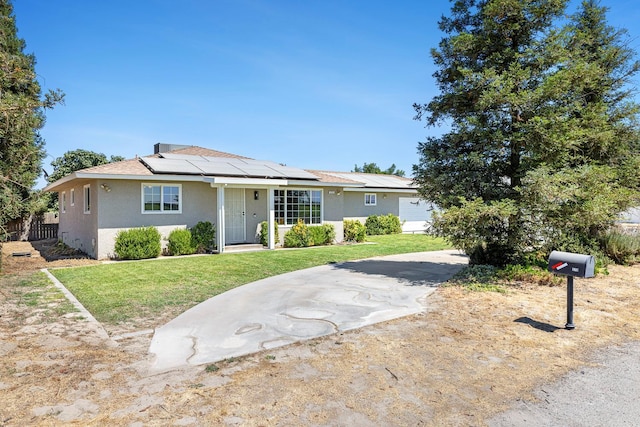 570 S Lassen Ave, Kerman, CA 93630 - view of front of home featuring stucco siding, solar panels, and a front lawn
