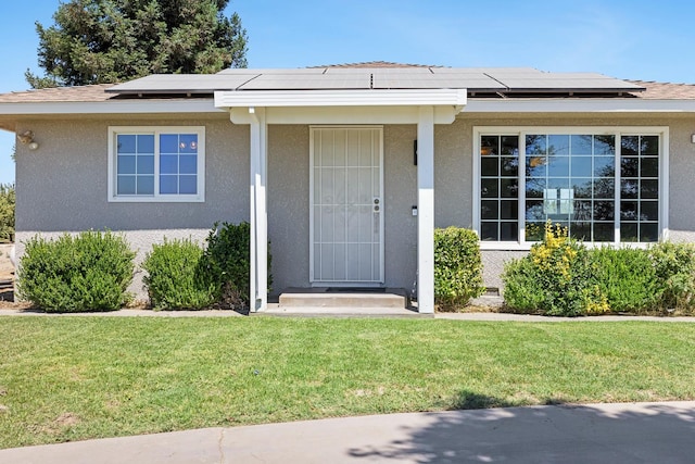 570 S Lassen Ave, Kerman, CA 93630 - property entrance with solar panels, a lawn, and stucco siding