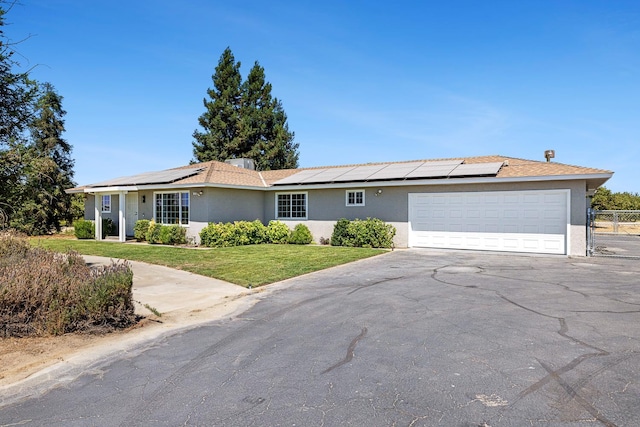 570 S Lassen Ave, Kerman, CA 93630 - ranch-style house with stucco siding, asphalt driveway, solar panels, and a garage