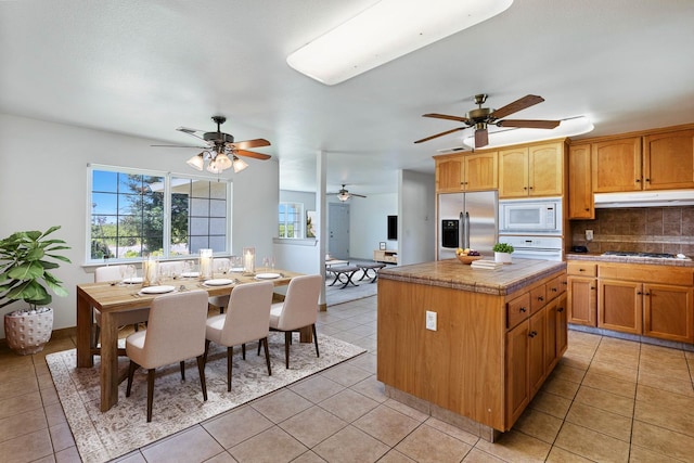 570 S Lassen Ave, Kerman, CA 93630 - kitchen featuring white appliances, ceiling fan, backsplash, a kitchen island, and tile counters