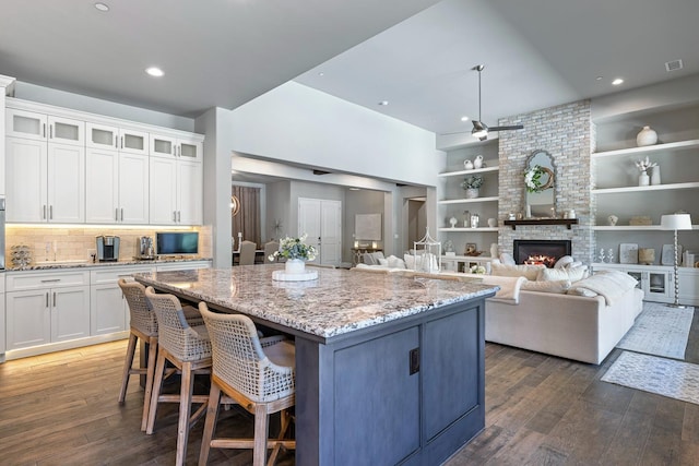 2706 Trenton Ave, Clovis, CA 93619 - kitchen with wood finished floors, light stone countertops, a center island, white cabinets, and recessed lighting