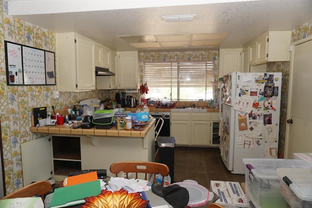 7637 Nixos Way, Sacramento, CA 95823 - kitchen featuring freestanding refrigerator, tile countertops, wallpapered walls, under cabinet range hood, and white cabinetry
