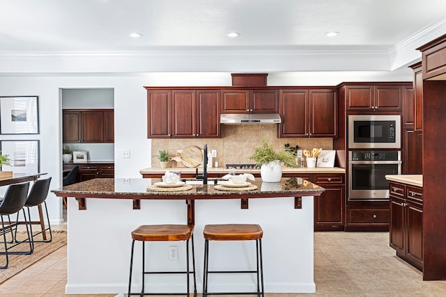 4160 N Creekbend, Clovis, CA 93619 - kitchen with oven, under cabinet range hood, built in microwave, light tile patterned flooring, and a kitchen bar