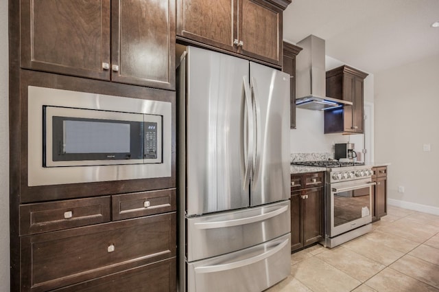 1728 E Green Sage Ave, Fresno, CA 93730 - kitchen featuring stainless steel appliances, wall chimney range hood, dark brown cabinets, light tile patterned floors, and light stone counters
