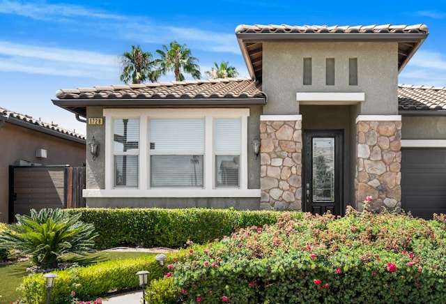 1728 E Green Sage Ave, Fresno, CA 93730 - mediterranean / spanish-style house featuring stucco siding, stone siding, a tiled roof, and a garage