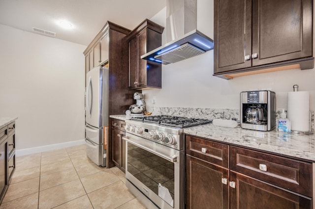 1728 E Green Sage Ave, Fresno, CA 93730 - kitchen featuring stainless steel appliances, wall chimney exhaust hood, dark brown cabinetry, light stone counters, and light tile patterned flooring