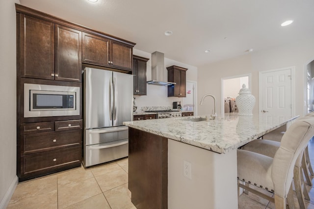 1728 E Green Sage Ave, Fresno, CA 93730 - kitchen with appliances with stainless steel finishes, wall chimney exhaust hood, light stone countertops, an island with sink, and a breakfast bar