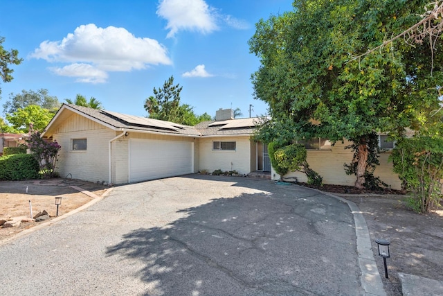 4678 N Thorne Ave, Fresno, CA 93704 - ranch-style home featuring brick siding, driveway, a garage, roof mounted solar panels, and a chimney
