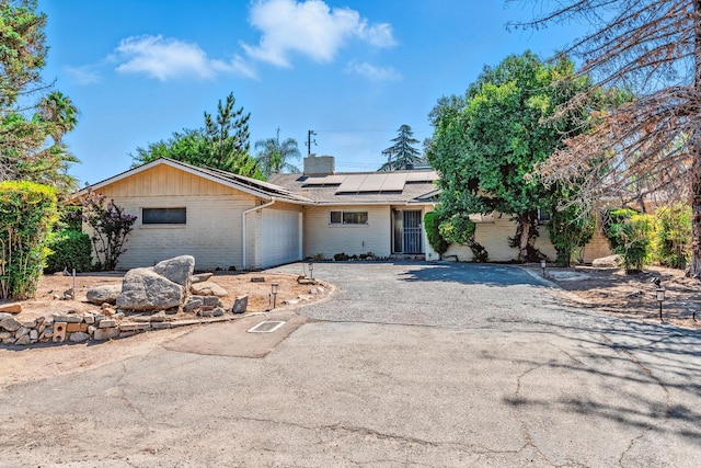 4678 N Thorne Ave, Fresno, CA 93704 - ranch-style home featuring an attached garage, brick siding, a chimney, driveway, and solar panels