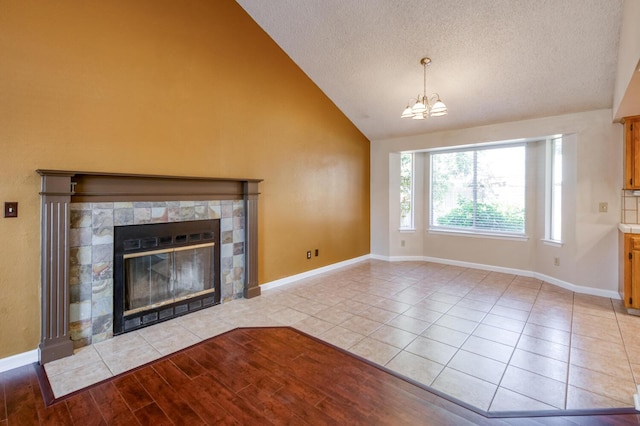 6283 N Gilroy Ave, Fresno, CA 93722 - unfurnished living room with a chandelier, a fireplace, a textured ceiling, tile patterned flooring, and high vaulted ceiling