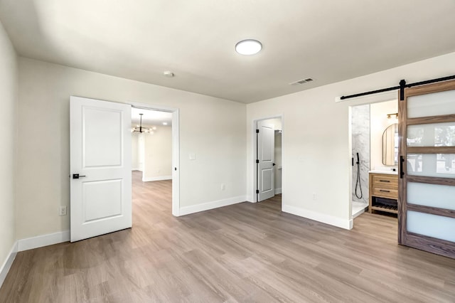 2643 B St, Selma, CA 93662 - unfurnished bedroom featuring light wood finished floors, a barn door, and a chandelier