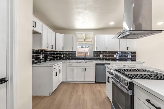 2643 B St, Selma, CA 93662 - kitchen featuring island exhaust hood, appliances with stainless steel finishes, light wood-style flooring, decorative backsplash, and white cabinetry