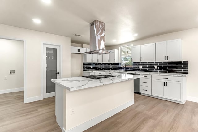 2643 B St, Selma, CA 93662 - kitchen with light wood-type flooring, decorative backsplash, island exhaust hood, white cabinetry, and recessed lighting