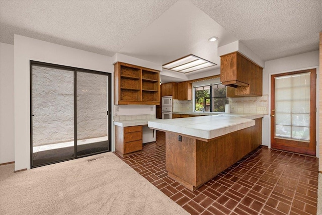 835 E Ashcroft Ave, Fresno, CA 93704 - kitchen featuring brown cabinets, open shelves, tasteful backsplash, a peninsula, and brick patterned floors