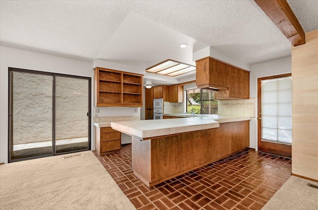 835 E Ashcroft Ave, Fresno, CA 93704 - kitchen featuring brown cabinets, a textured ceiling, open shelves, a peninsula, and brick patterned floors