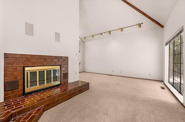 835 E Ashcroft Ave, Fresno, CA 93704 - unfurnished living room with a brick fireplace, carpet flooring, beamed ceiling, high vaulted ceiling, and rail lighting