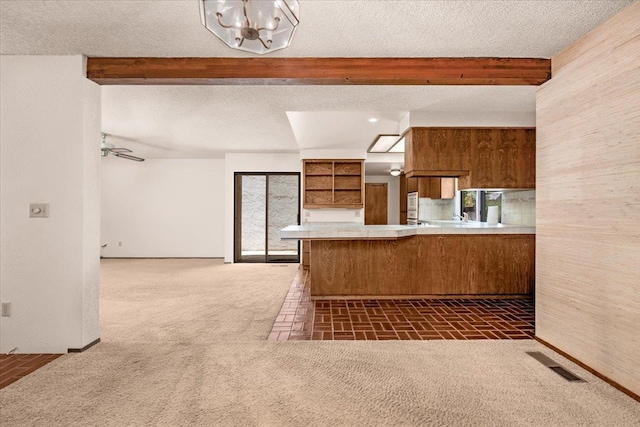 835 E Ashcroft Ave, Fresno, CA 93704 - kitchen featuring beamed ceiling, a peninsula, brown cabinets, carpet, and a chandelier