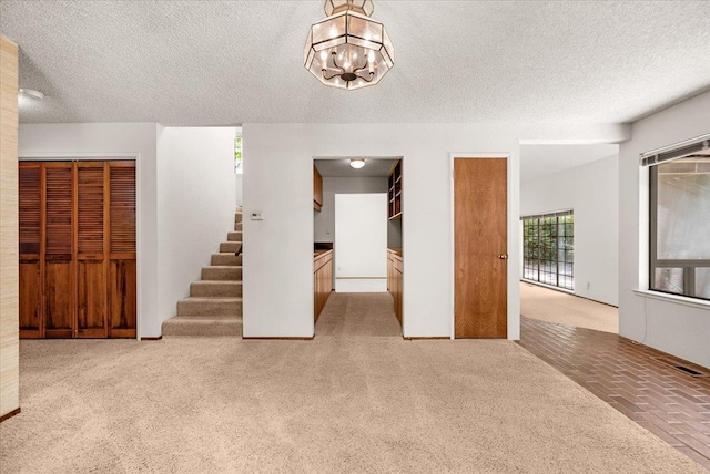 835 E Ashcroft Ave, Fresno, CA 93704 - unfurnished living room with a textured ceiling, carpet flooring, stairway, and a chandelier