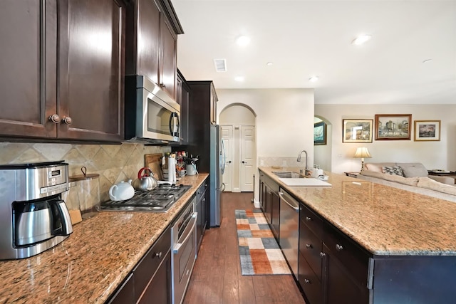 11319 N Via Napoli Dr, Fresno, CA 93730 - kitchen with appliances with stainless steel finishes, arched walkways, open floor plan, dark wood-style floors, and light stone counters