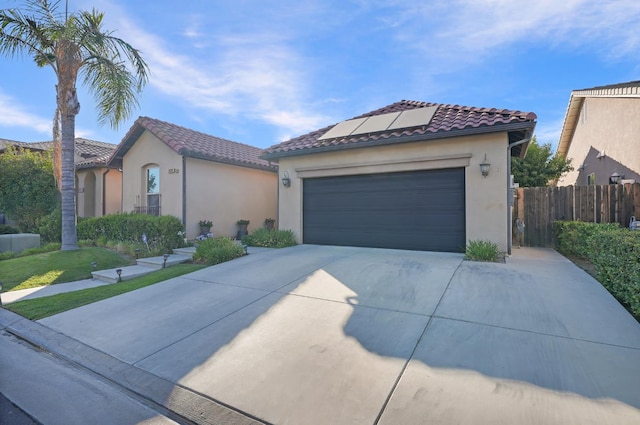 11319 N Via Napoli Dr, Fresno, CA 93730 - mediterranean / spanish-style house featuring driveway, roof mounted solar panels, stucco siding, a tiled roof, and a garage