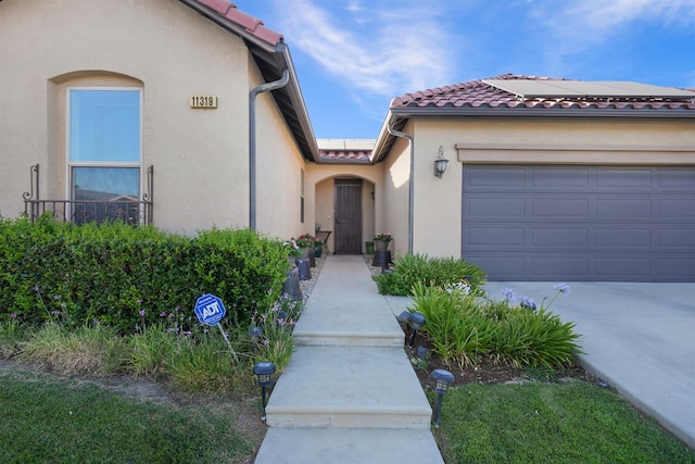 11319 N Via Napoli Dr, Fresno, CA 93730 - view of front of property featuring a tiled roof, stucco siding, an attached garage, solar panels, and driveway