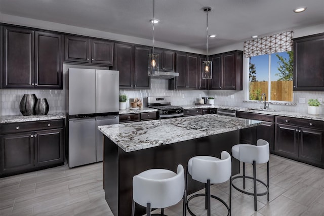 4553 Griffith Ave, Clovis, CA 93619 - kitchen featuring appliances with stainless steel finishes, a kitchen bar, decorative backsplash, light stone counters, and recessed lighting