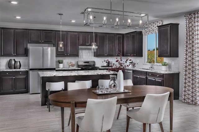 4553 Griffith Ave, Clovis, CA 93619 - kitchen with stainless steel appliances, under cabinet range hood, dark brown cabinets, tasteful backsplash, and recessed lighting