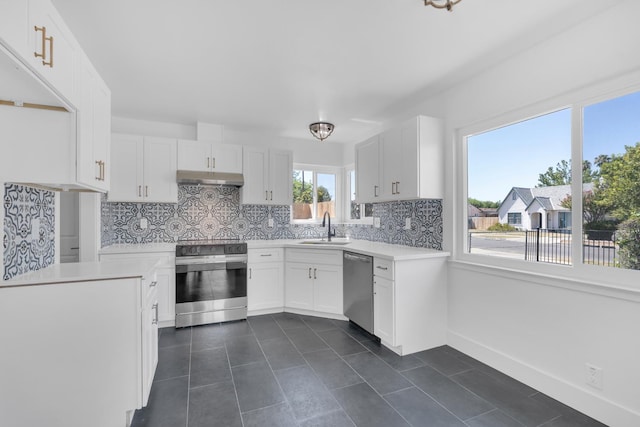 4596 E Huntington Ave, Fresno, CA 93702 - kitchen with appliances with stainless steel finishes, under cabinet range hood, decorative backsplash, light countertops, and dark tile patterned floors