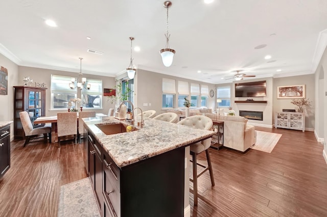 11617 N Bella Verde Ave, Fresno, CA 93730 - kitchen featuring ornamental molding, ceiling fan, recessed lighting, a glass covered fireplace, and a breakfast bar area