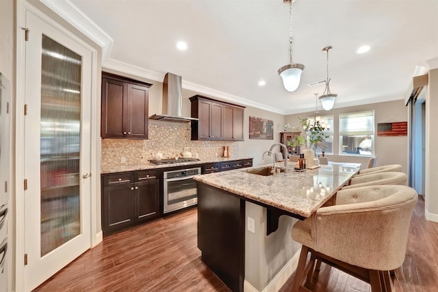 11617 N Bella Verde Ave, Fresno, CA 93730 - kitchen featuring stainless steel appliances, wall chimney range hood, a breakfast bar, tasteful backsplash, and dark brown cabinetry