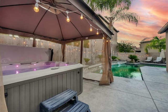 11617 N Bella Verde Ave, Fresno, CA 93730 - pool at dusk featuring a hot tub, a gazebo, a fenced backyard, and a patio area