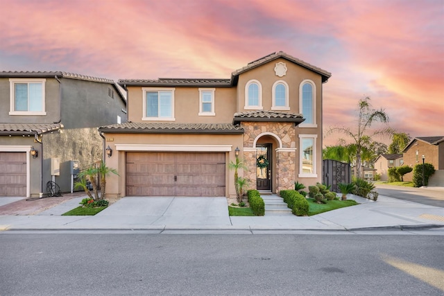 11617 N Bella Verde Ave, Fresno, CA 93730 - mediterranean / spanish house with driveway, stone siding, an attached garage, a tiled roof, and stucco siding