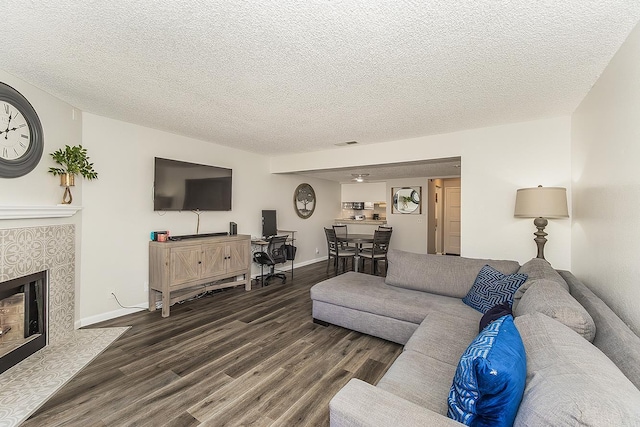 4885 N Backer Ave Unit 113, Fresno, CA 93726 - living area featuring dark wood-style floors, a textured ceiling, and a tile fireplace