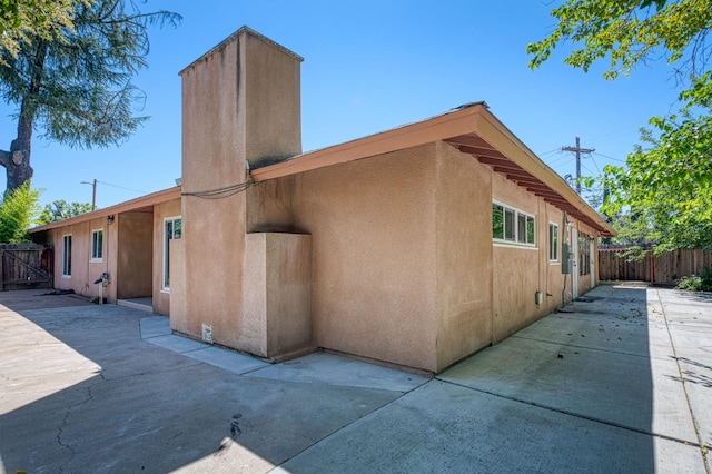 545 W Fedora Ave, Fresno, CA 93705 - view of side of property featuring a patio, a fenced backyard, stucco siding, and a chimney