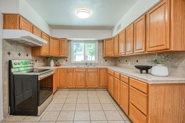 545 W Fedora Ave, Fresno, CA 93705 - kitchen featuring black / electric stove, under cabinet range hood, light countertops, and tasteful backsplash