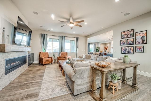 924 Orchard Hills Rd, Madera, CA 93636 - living room with light wood-style flooring, a glass covered fireplace, a ceiling fan, and recessed lighting