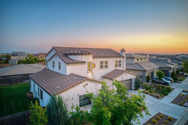 924 Orchard Hills Rd, Madera, CA 93636 - back of house at dusk with stucco siding, driveway, a residential view, and a tile roof