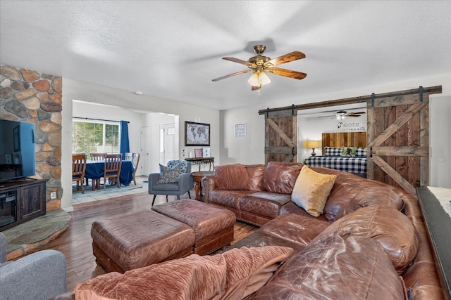 53401 Timberview Rd, North Fork, CA 93643 - living area with a barn door, wood finished floors, a wood stove, and a ceiling fan
