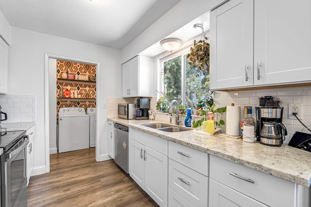 4679 E Pitt Ave, Fresno, CA 93725 - kitchen with washing machine and clothes dryer, stainless steel appliances, backsplash, white cabinetry, and wood finished floors