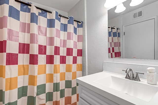 4679 E Pitt Ave, Fresno, CA 93725 - bathroom with a textured wall, vanity, tasteful backsplash, and a shower with curtain